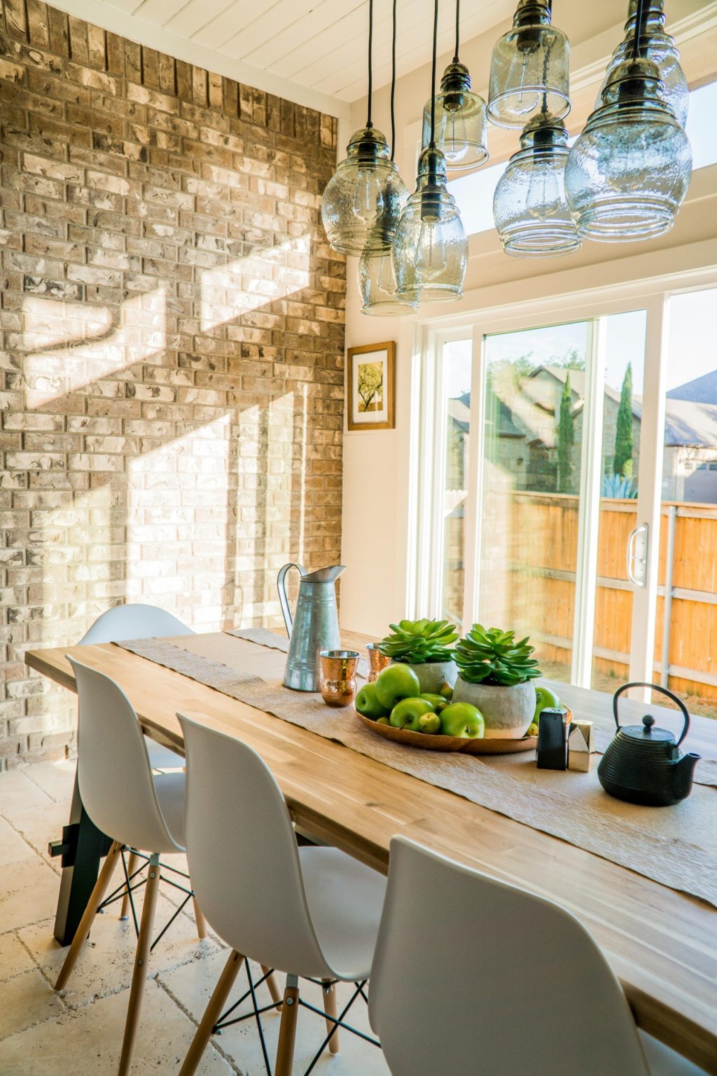 Table en bois massif avec des chaises blanches dans une salle lumineuse.